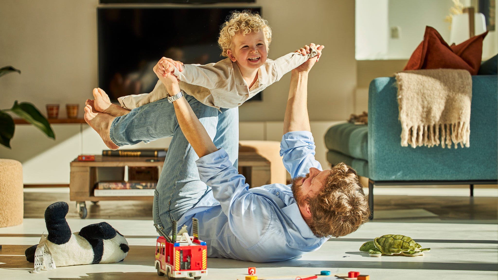Μπαμπάς και παιδί παίζουν μαζί χαρούμενοι απολαμβάνοντας τη ζεστασιά της ενδοδαπέδιας θέρμανσης