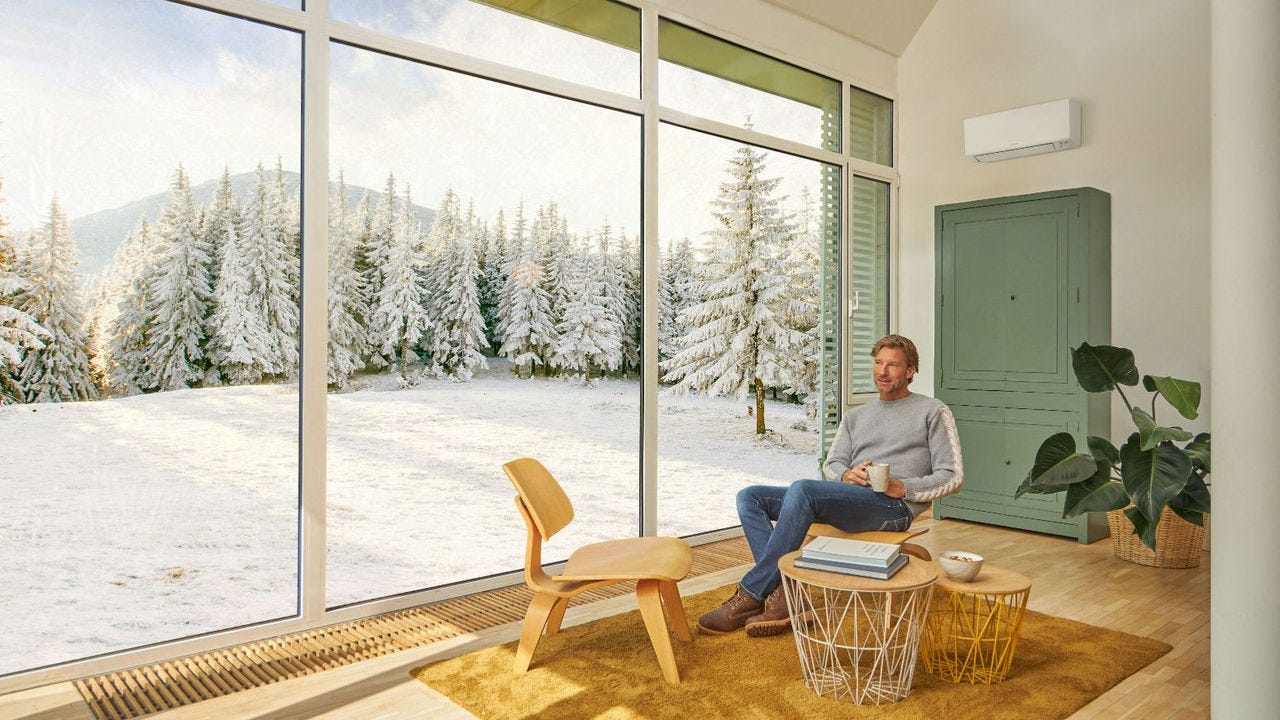 Άντρας κάθεται στον καναπέ και απολαμβάνει τη θέρμανση με κλιματιστικό