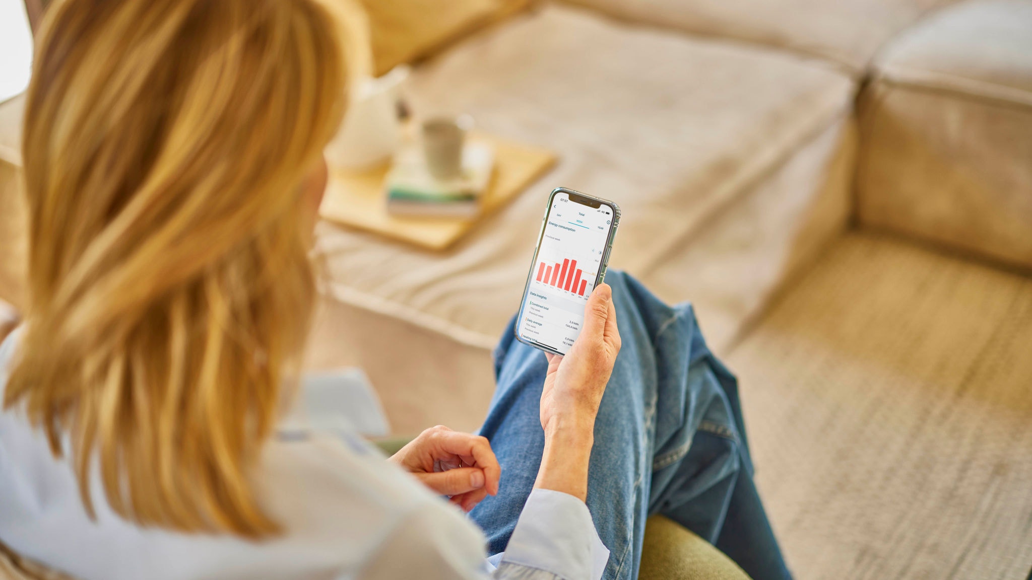 Γυναίκα που ελέγχει τη μονάδα εξαερισμού της χρησιμοποιώντας την εφαρμογή Onecta