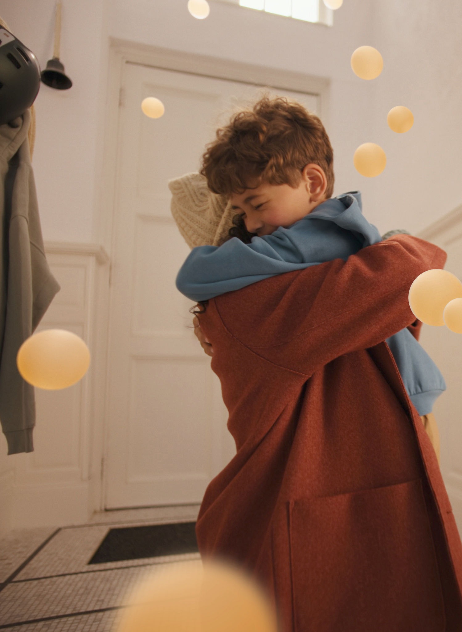 Μητέρα και γιος μοιράζονται μια ζεστή αγκαλιά σε έναν κομψό, γαλήνιο χώρο, απολαμβάνοντας την άνεση που προσφέρει μια αντλία θερμότητας αέρα σε αέρα Daikin