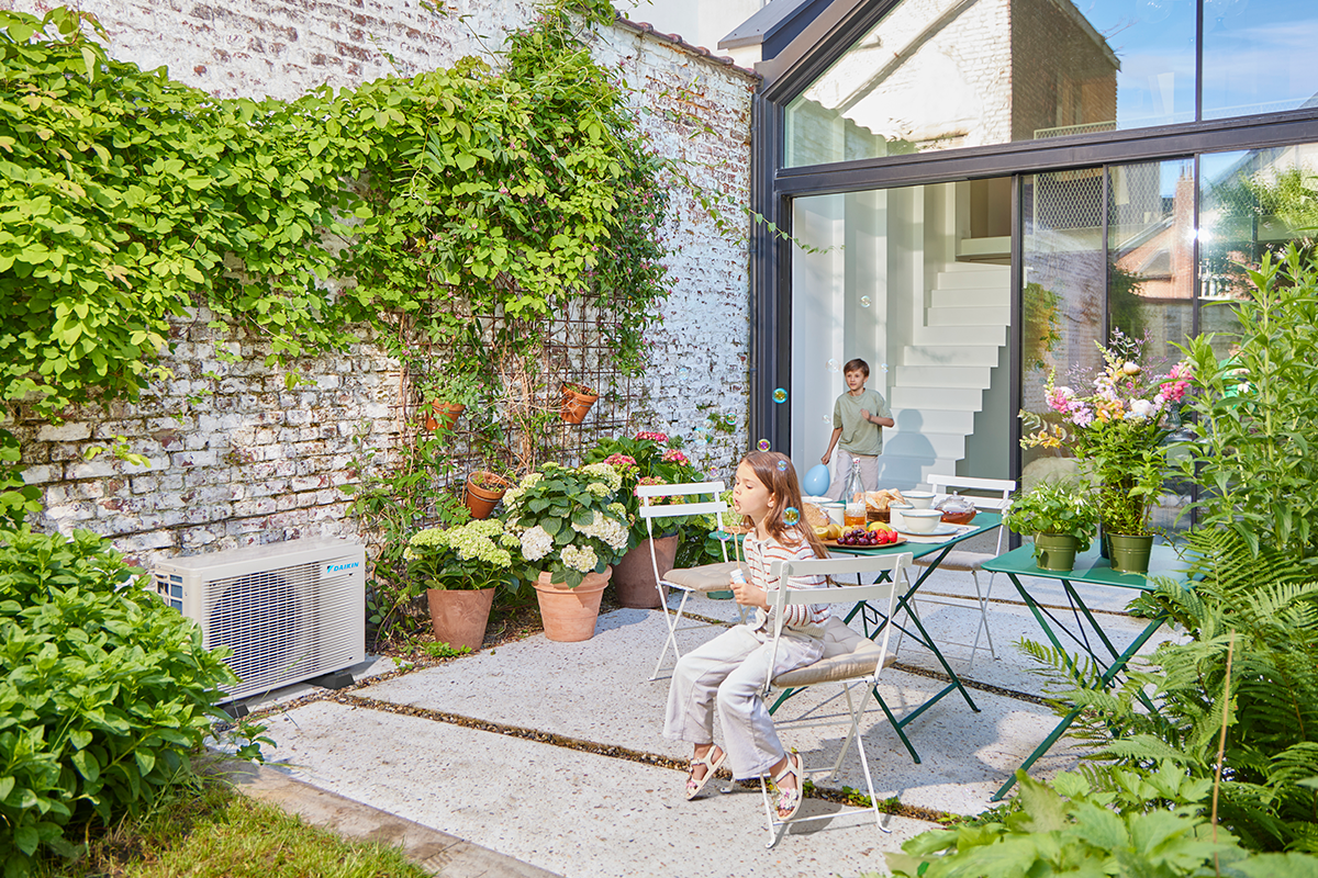 Παιδιά παίζουν μπίλιες σε βεράντα στον κήπο δίπλα σε μια εξωτερική αντλία θερμότητας